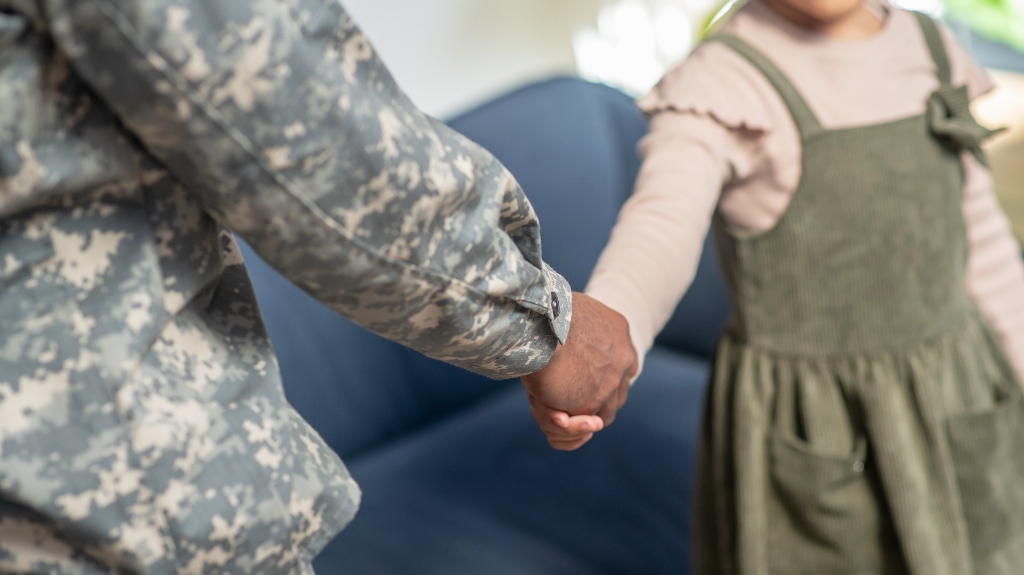 Military man shaking hand to little daughter