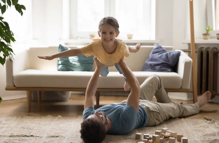 Father is playing with his happy little daughter