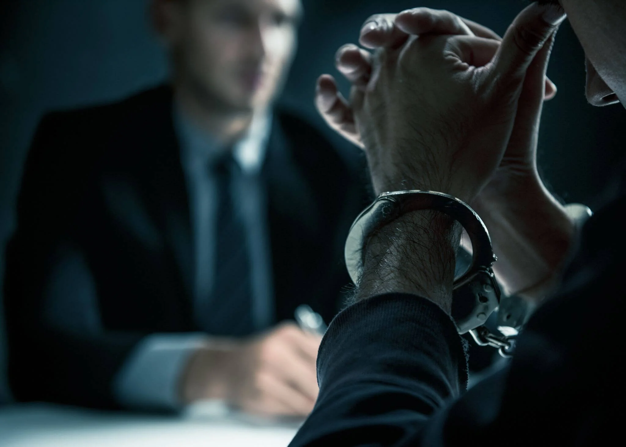a handcuffed man sitting in front of an investigator
