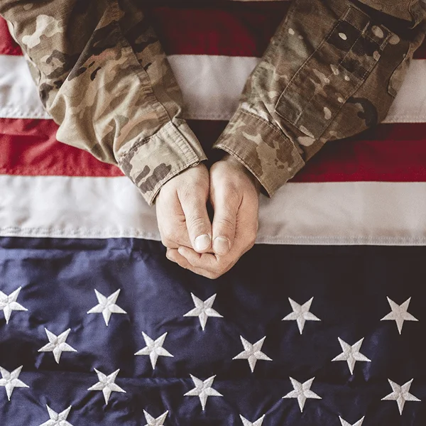 A close-up of clasped hands resting on an American flag, symbolizing unity and patriotism.