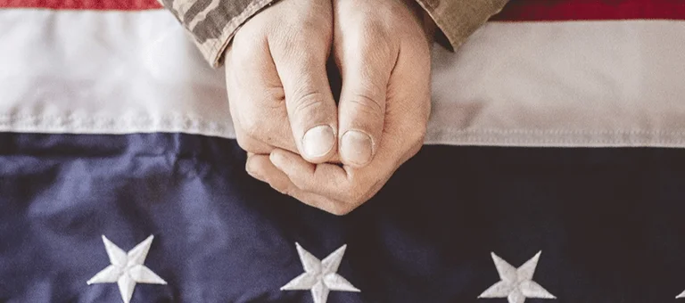 A close-up of clasped hands resting on an American flag, symbolizing unity and patriotism.