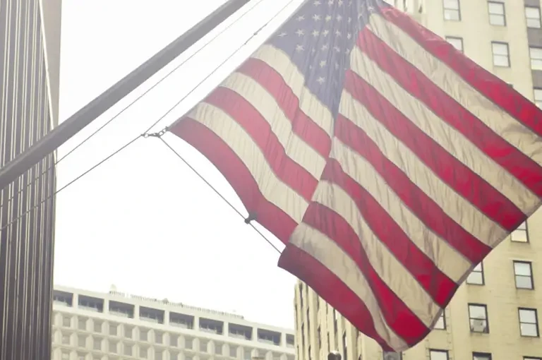 American flag hanging between skyscrapers in a city