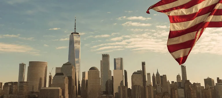 A wide-angle view of the New York skyline, featuring tall buildings and the One World Trade Center, with an American flag in the foreground.
