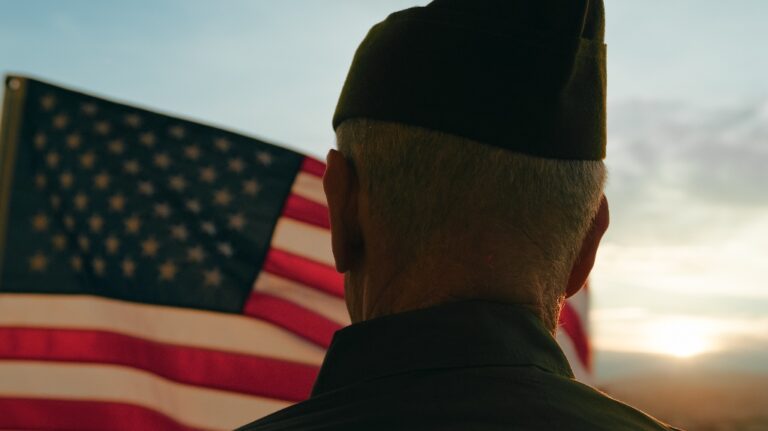 veteran stands in front of an American flag