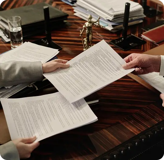 Two people exchanging legal documents during divorce mediation.